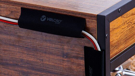 Cables organized with with VELCRO® Brand Cable Sleeves, stuck to the back of a desk