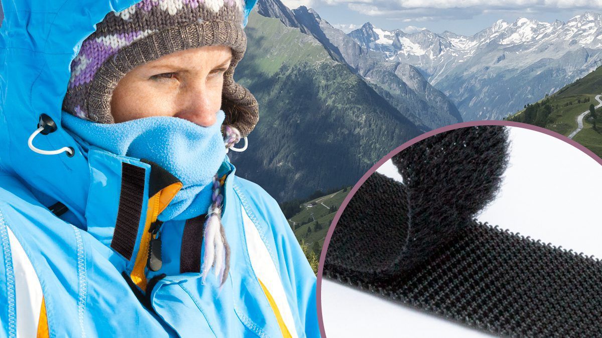Person in outdoor gear with VELCRO® Brand hook and loop fasteners, set against a mountain landscape, highlighting performance in rugged conditions.