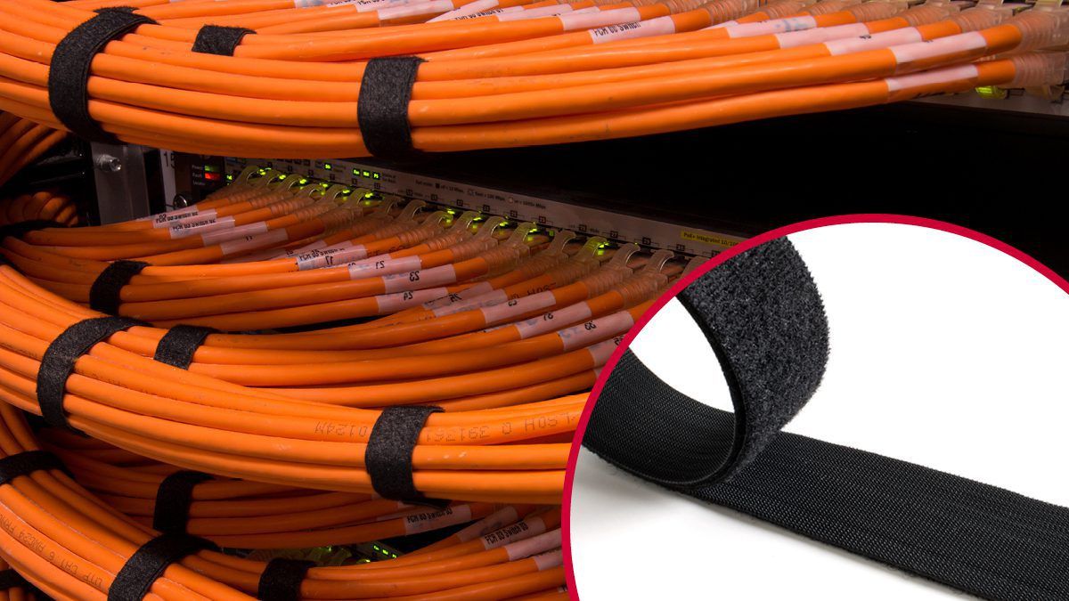 VELCRO® Brand hook and loop fasteners securing orange network cables in a data center rack, ensuring organized industrial cable management.