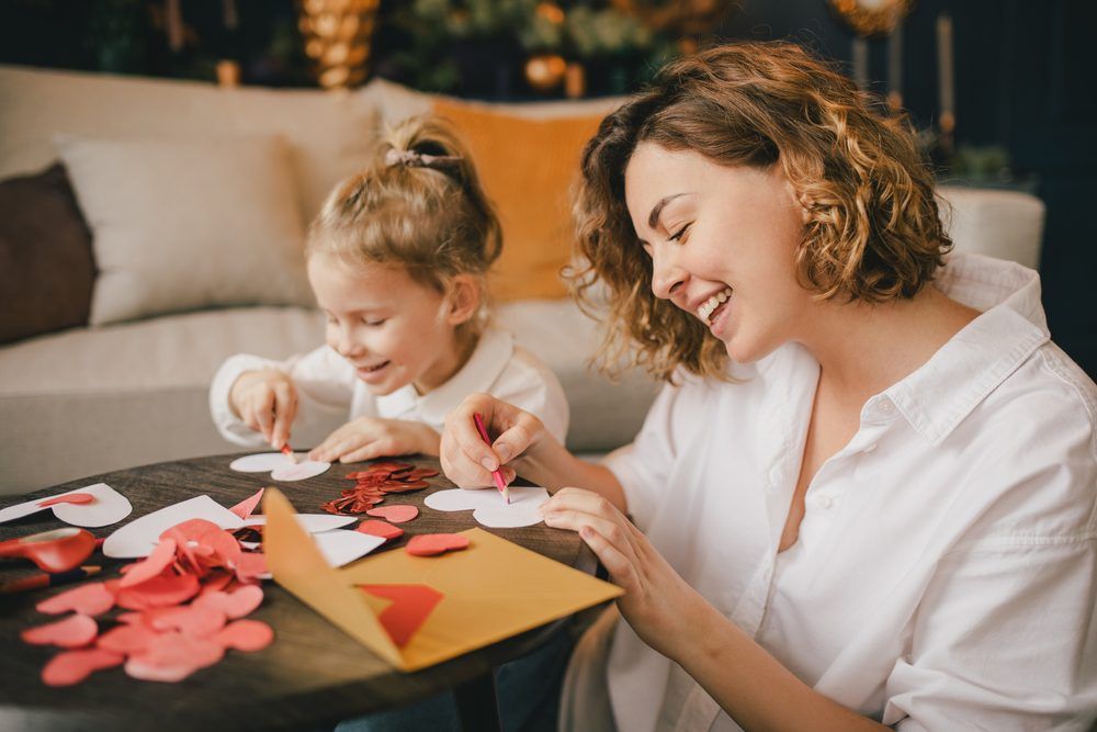 Mom and child doing valentines day crafts at living room table