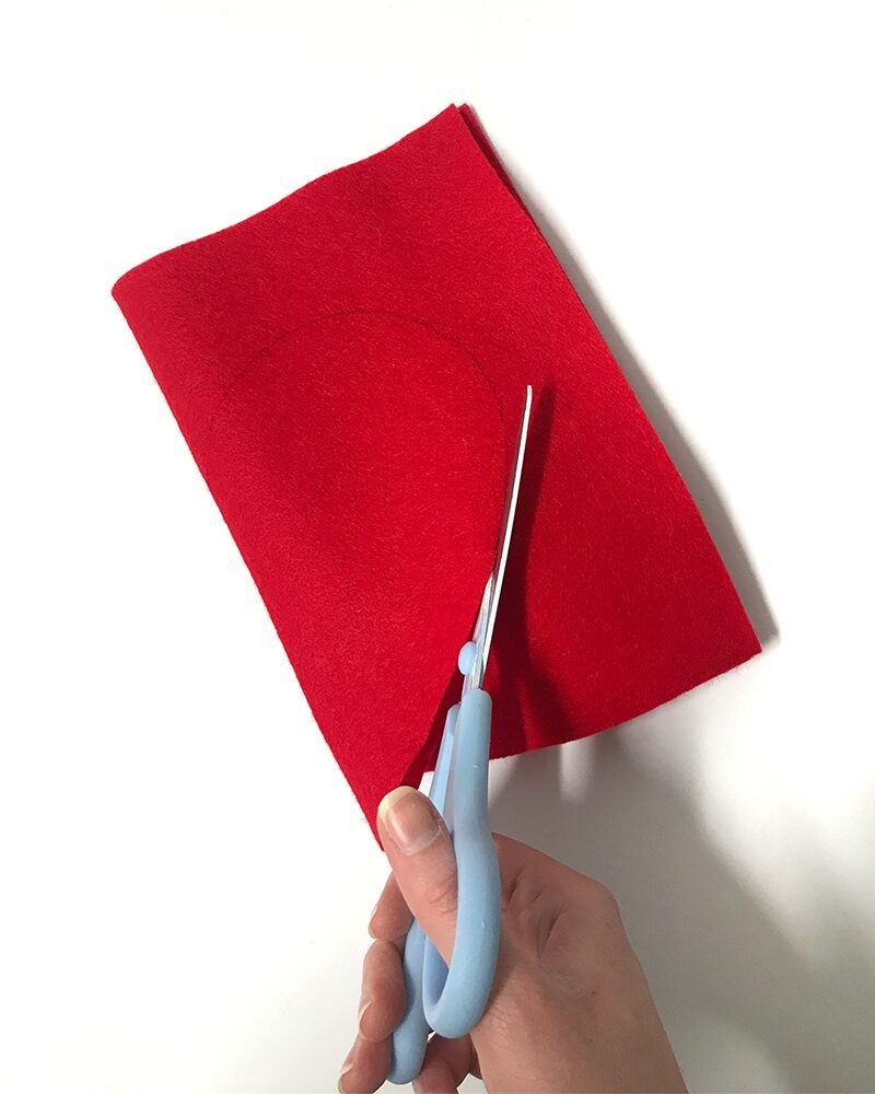 Scissors cutting heart from red felt for Valentines Day craft.