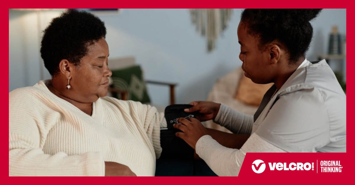 Home health nurse wrapping blood pressure band around patient.