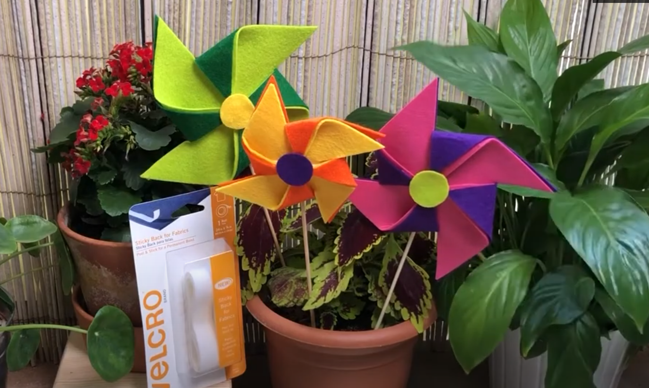 Three handmade felt pinwheels stuck in a flower pot.
